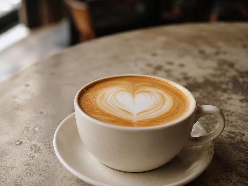 A latte with a heart poured in the foam, on a café table